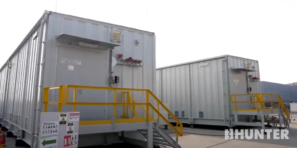 Line of white custom modular control room modules with yellow railings